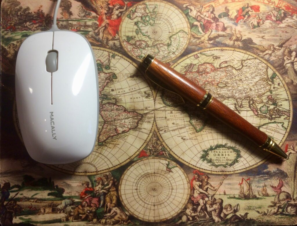 Beautiful wood pen on map of the world, next to computer mouse.